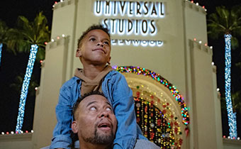 Father and son in front of Universal Studios with palm trees lit up