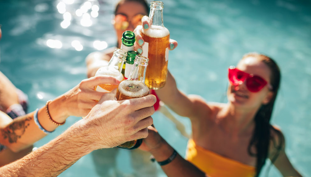 people doing a cheers with beer in the pool